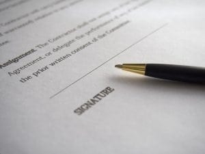 A written agreement with pen near the "SIGNATURE" line