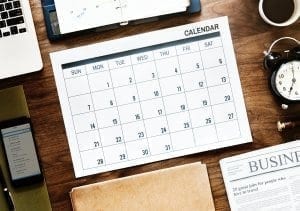 Desk with calendar, newspaper, coffee, and clock