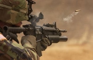 Man in camo shooting a large gun