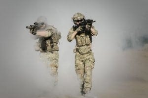 Military men emerging from smoke with guns pointed