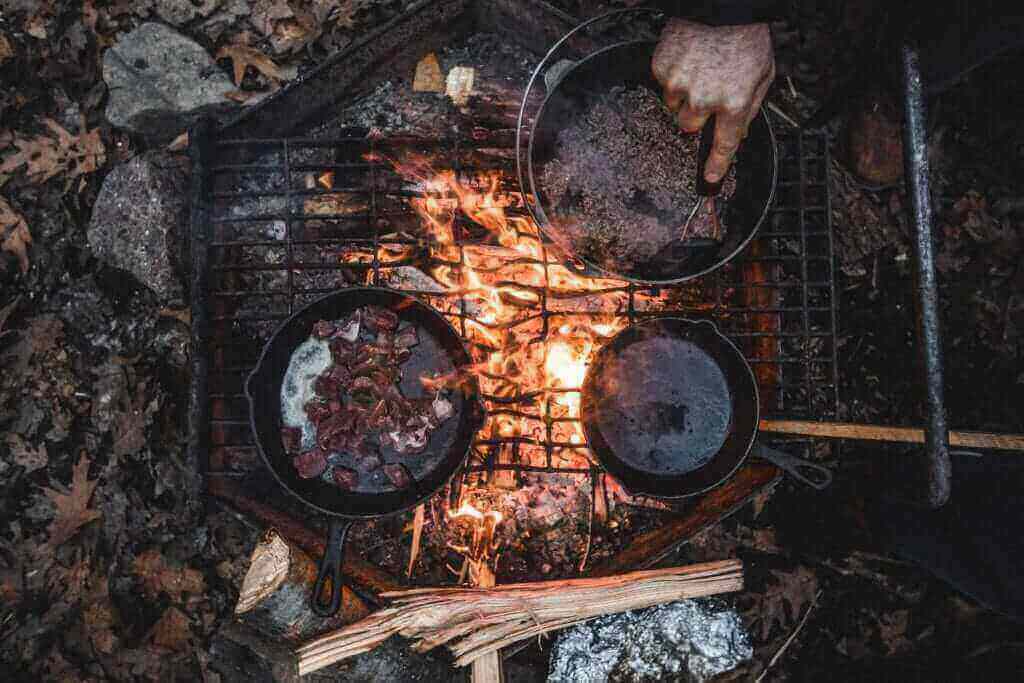 Cast iron pans cooking food over fire