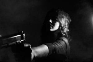 Woman holding gun in the shadows
